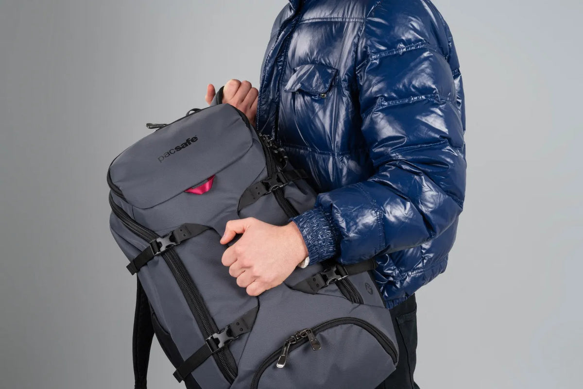 Pacsafe Venturesafe EXP35 Anti-Theft 35L Travel Backpack in Slate, carried by its haul handle against the chest, straps stowed