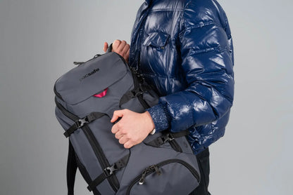 Pacsafe Venturesafe EXP35 Anti-Theft 35L Travel Backpack in Slate, carried by its haul handle against the chest, straps stowed