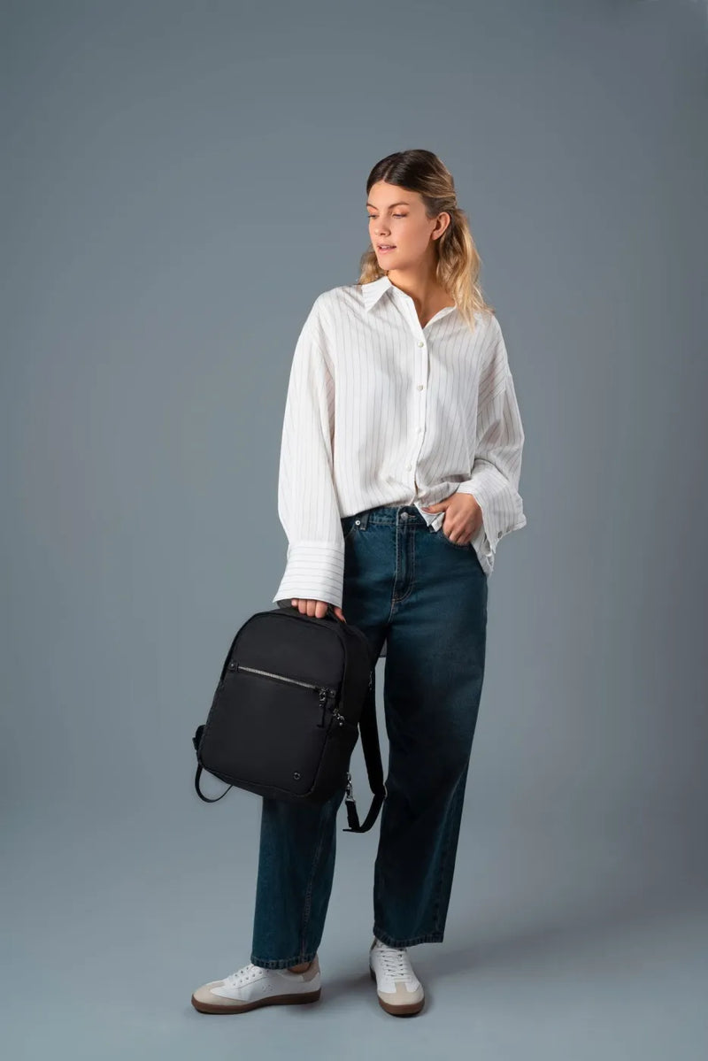 Pacsafe W 10L Anti-theft 13" Laptop Backpack in Black, held by the top handle at the side of a woman in jeans