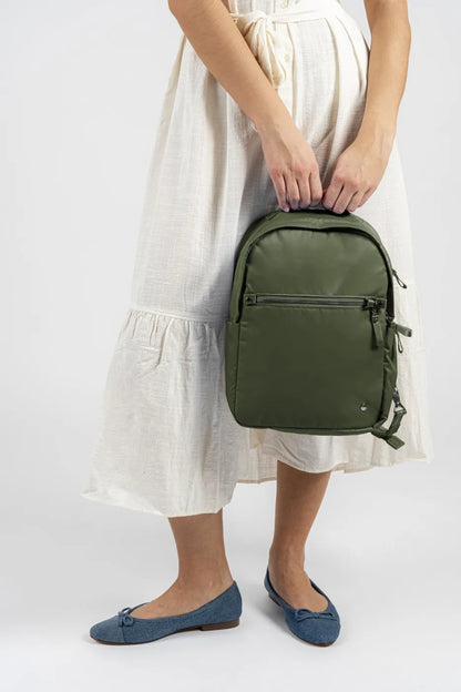 Pacsafe W 10L Anti-theft 13" Laptop Backpack in Olive, held by its grab handle at the side of a woman in a cream dress