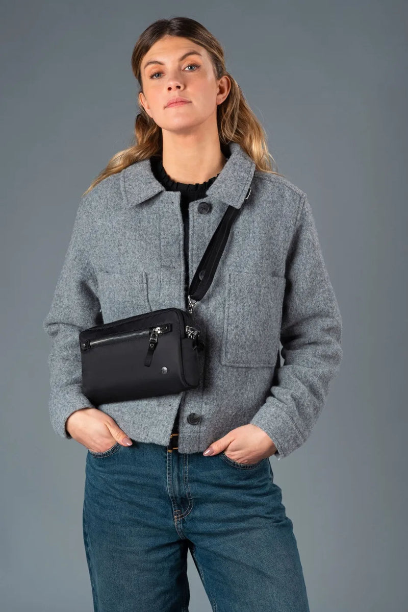 Pacsafe W Anti-theft 3-in-1 Sling Bag in Black, worn crossbody at the waist over a grey wool jacket