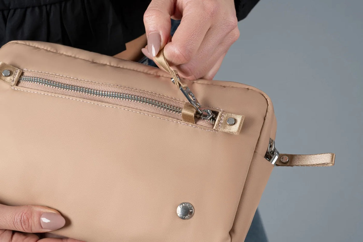 Pacsafe W Anti-theft 3-in-1 Sling Bag in Taupe, the security zip being unhooked from its catch