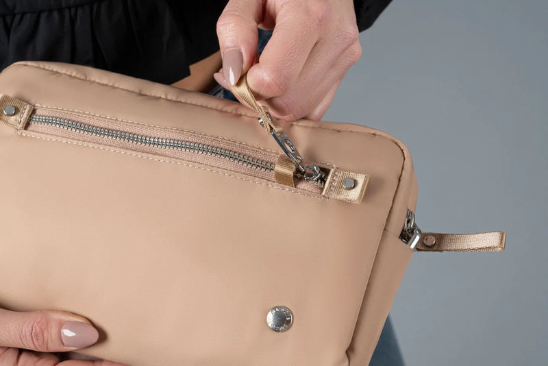 Pacsafe W Anti-theft 3-in-1 Sling Bag in Taupe, the security zip being unhooked from its catch
