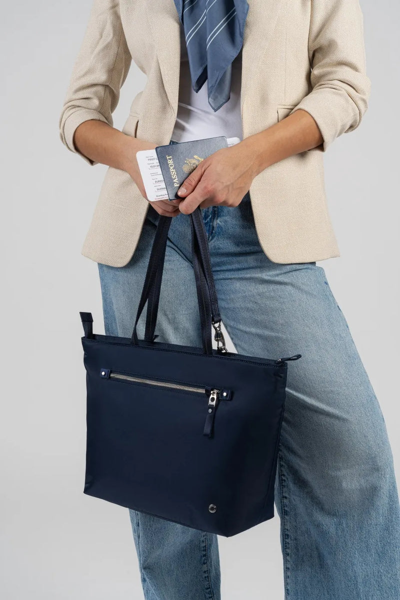 Pacsafe W Anti-theft Carryall 13" Laptop Tote in Navy, a passport and boarding pass being lifted from the bag at the hip
