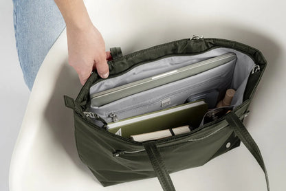 Pacsafe W Anti-theft Carryall 13" Laptop Tote in Olive, open on a white chair, a laptop and papers in the padded compartment