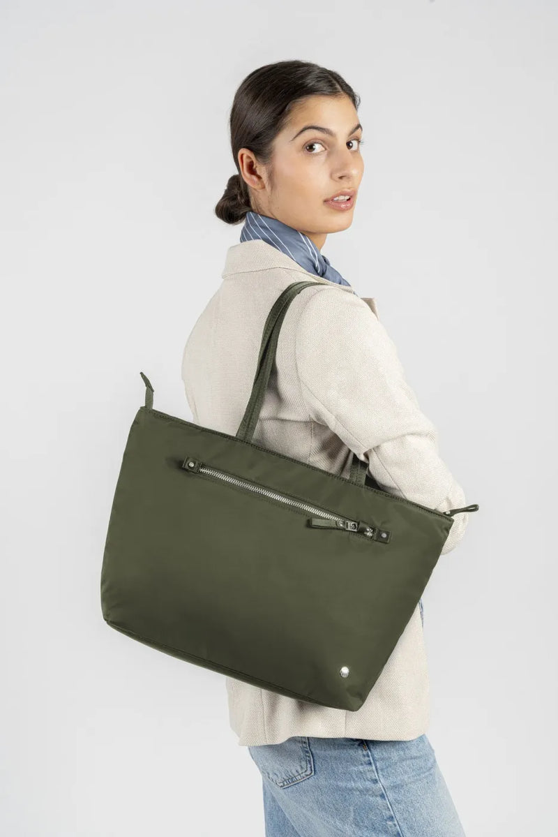 Pacsafe W Anti-theft Carryall 13" Laptop Tote in Olive, carried on the shoulder by a woman in a cream shirt, seen from behind