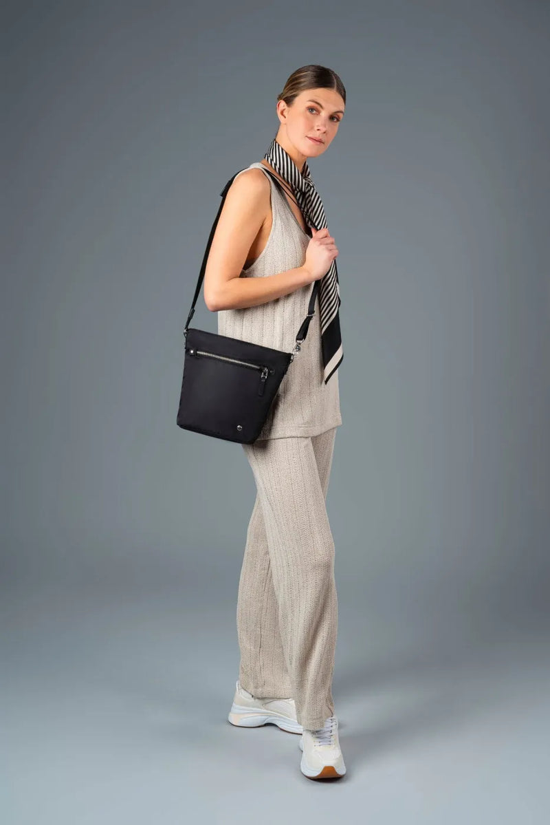 Pacsafe W Anti-theft Crossbody Bag in Black, worn crossbody at the hip, seen from behind over the shoulder