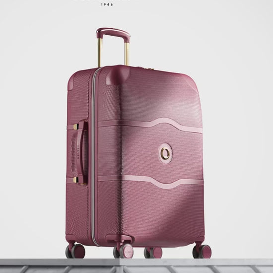 Delsey Chatelet Air 2.0 80th anniversary suitcase in burgundy: dual-density wheels, the double-layer zip teeth and lock, the blue patterned deluxe lining, then the case on a stone plinth