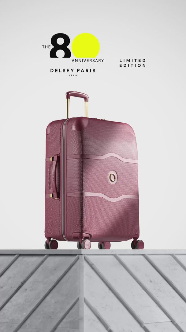 Delsey Chatelet Air 2.0 80th anniversary suitcase in burgundy: dual-density wheels, the double-layer zip teeth and lock, the blue patterned deluxe lining, then the case on a stone plinth