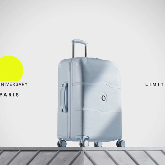 Delsey Chatelet Air 2.0 80th anniversary suitcase in light blue: dual-density wheels, the double-layer zip teeth and lock, the blue patterned deluxe lining, then the case on a stone plinth