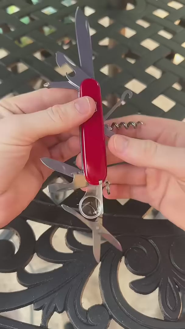 Victorinox Swiss Army Knife in red, its multipurpose hook untying a knot in a cord, propping up a phone, pulling an oven rack and lifting a ring-pull can lid