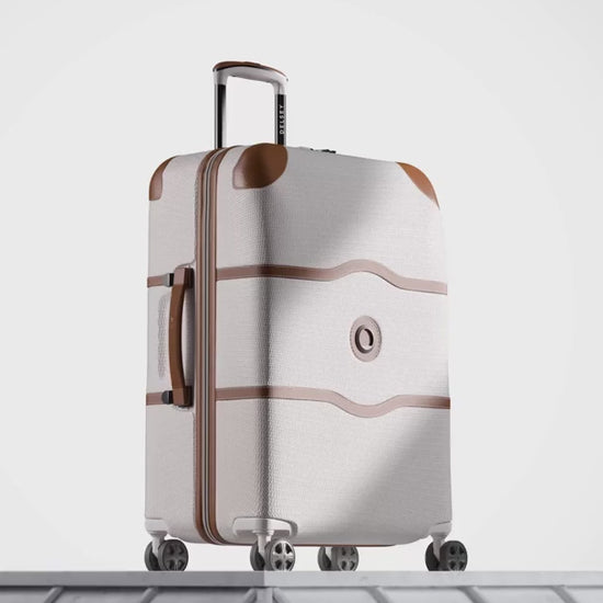 Delsey Chatelet Air 2.0 suitcase in angora white with tan trim: dual-density wheels, the double-layer zip teeth and lock, the red patterned deluxe lining, then the case on a stone plinth