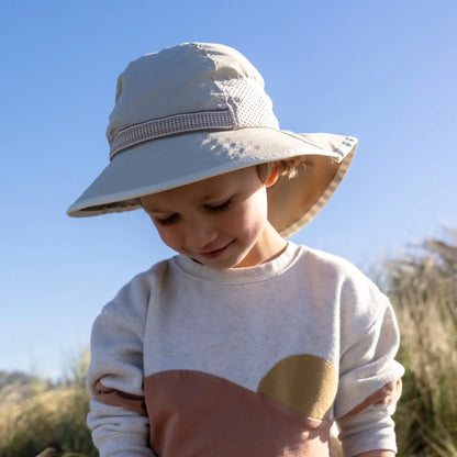A child wearing a Sunday Afternoons Kids Play Hat on a beach