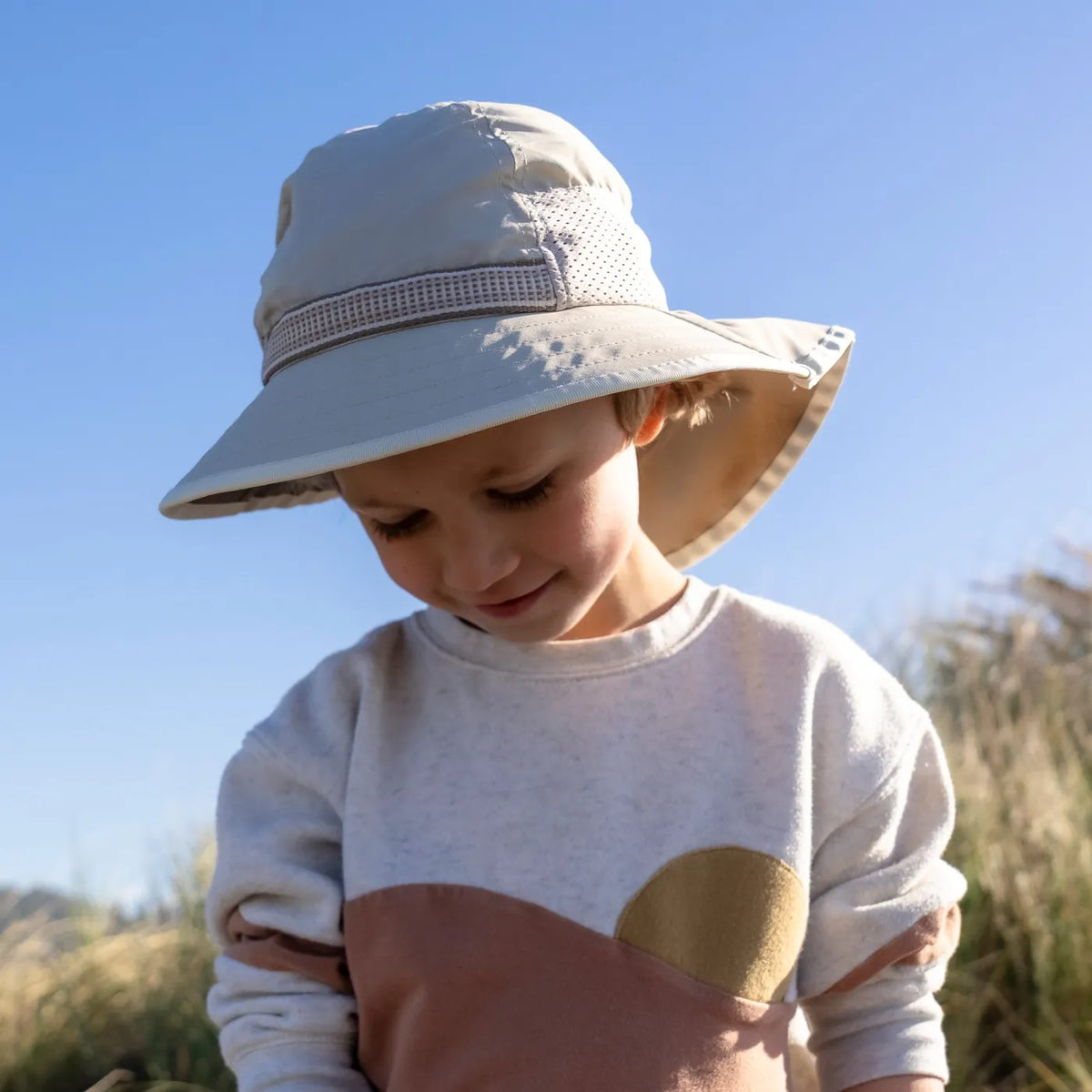A child wearing a Sunday Afternoons Kids Play Hat on a beach